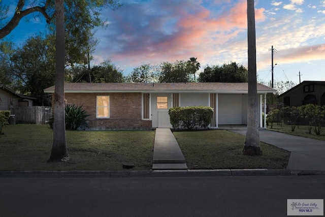 single story home featuring driveway, a front lawn, fence, and brick siding