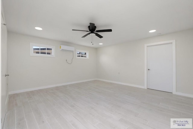 unfurnished room featuring light wood-style flooring, baseboards, an AC wall unit, and recessed lighting