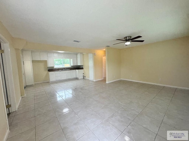 1017 E Austin Ave, Harlingen, TX 78550 - unfurnished living room featuring light tile patterned flooring, ceiling fan, a textured ceiling, and baseboards