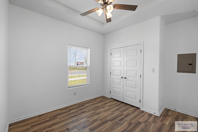 unfurnished bedroom featuring a closet, electric panel, ceiling fan, and dark wood-type flooring