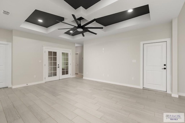 unfurnished room with ceiling fan, french doors, a tray ceiling, and light hardwood / wood-style floors