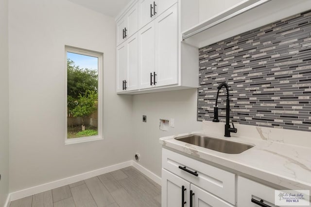 clothes washing area featuring sink, hookup for a washing machine, electric dryer hookup, and cabinets