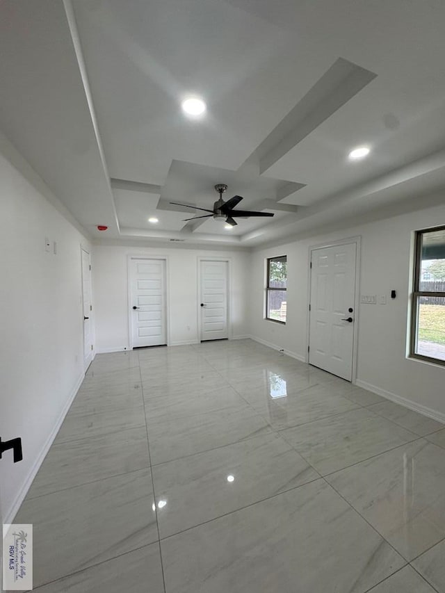 empty room with a raised ceiling and ceiling fan