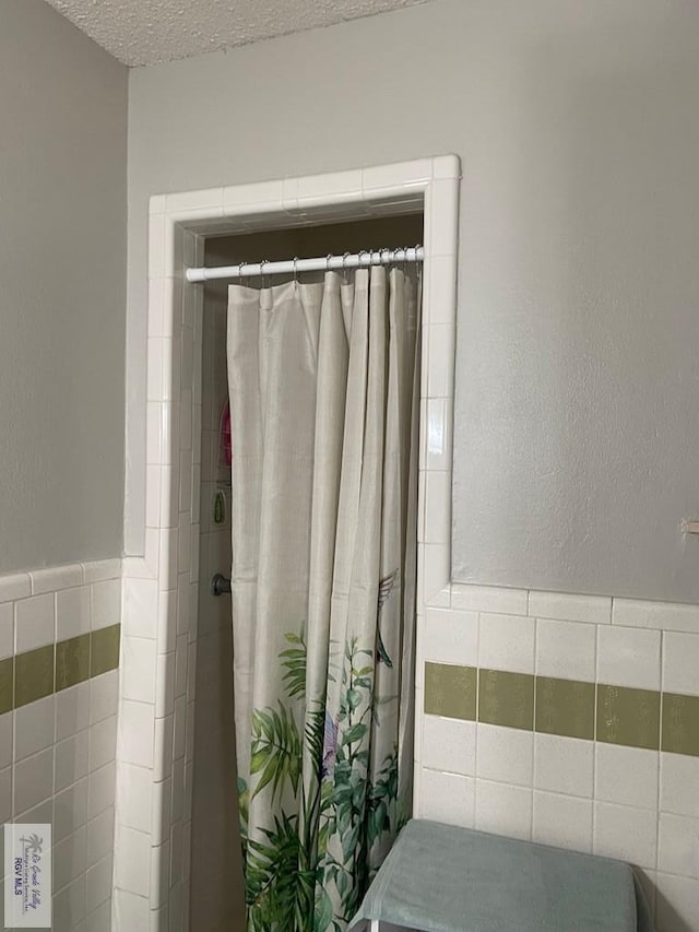 bathroom featuring a textured ceiling and tile walls