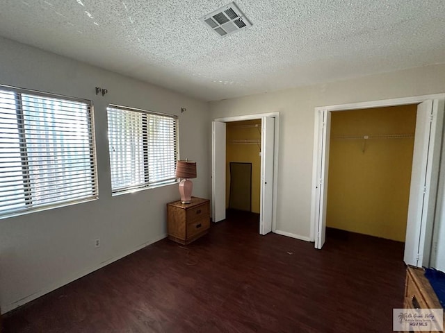 unfurnished bedroom featuring a textured ceiling, a closet, and dark wood-type flooring