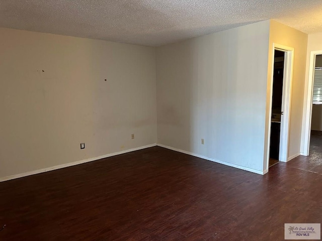 spare room with a textured ceiling and dark hardwood / wood-style floors