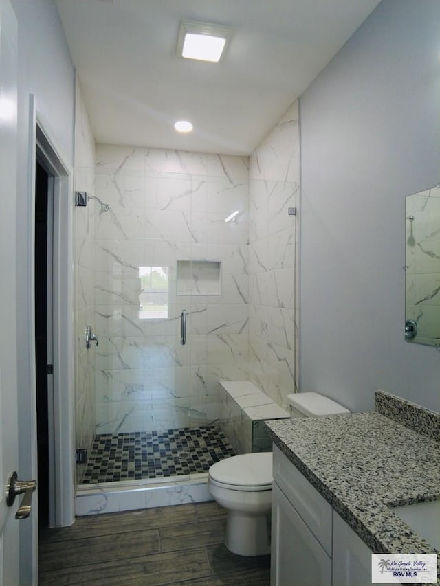 bathroom featuring hardwood / wood-style flooring, vanity, toilet, and walk in shower