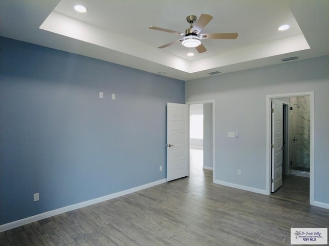 unfurnished room featuring ceiling fan, wood-type flooring, and a raised ceiling