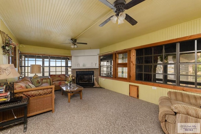 living room with carpet, ceiling fan, and a large fireplace