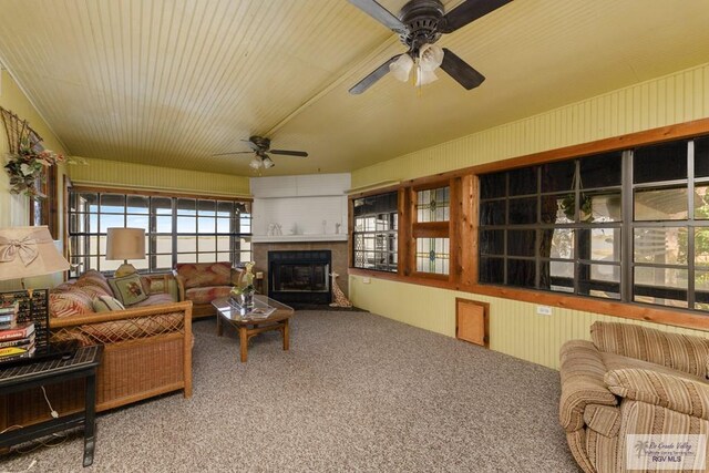 living room with carpet, ceiling fan, and a large fireplace