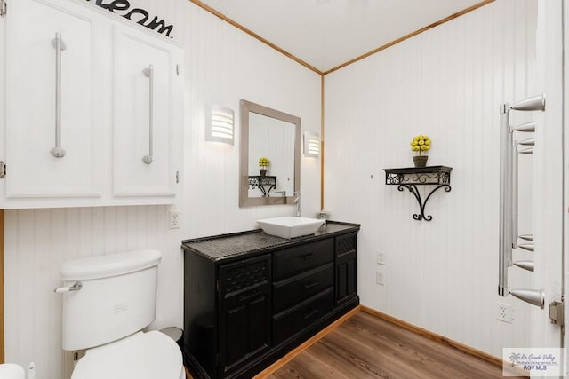 bathroom with toilet, vanity, ornamental molding, and hardwood / wood-style flooring