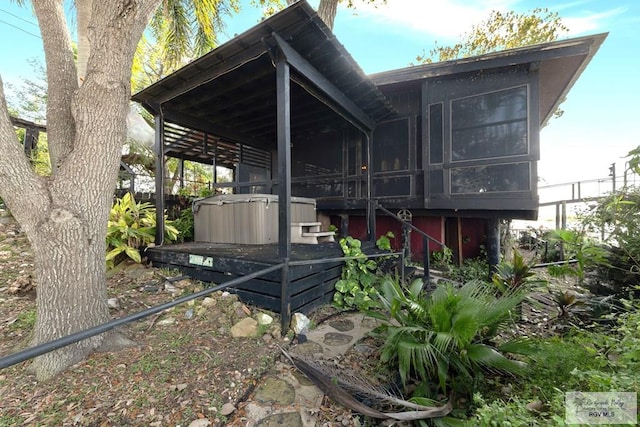 view of home's exterior with a hot tub and a sunroom