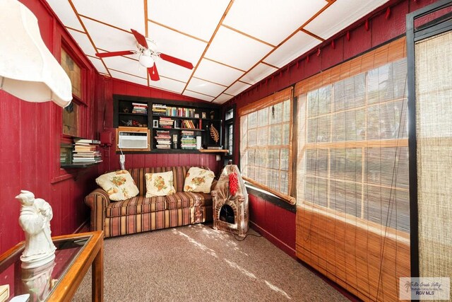 sitting room featuring plenty of natural light, wood walls, and vaulted ceiling