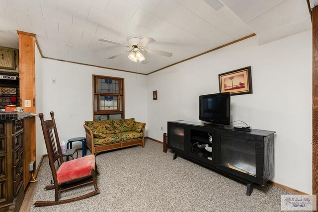 carpeted living room with ceiling fan and crown molding