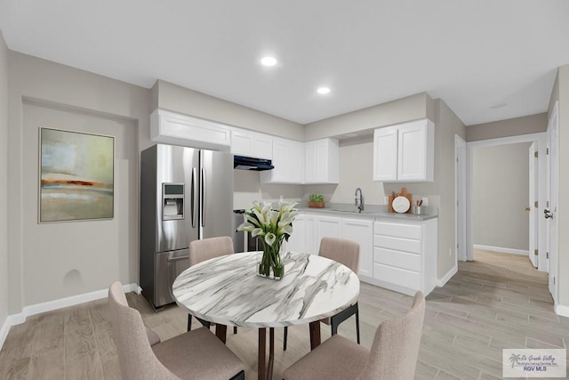 kitchen featuring stainless steel refrigerator with ice dispenser, ventilation hood, sink, light hardwood / wood-style flooring, and white cabinetry