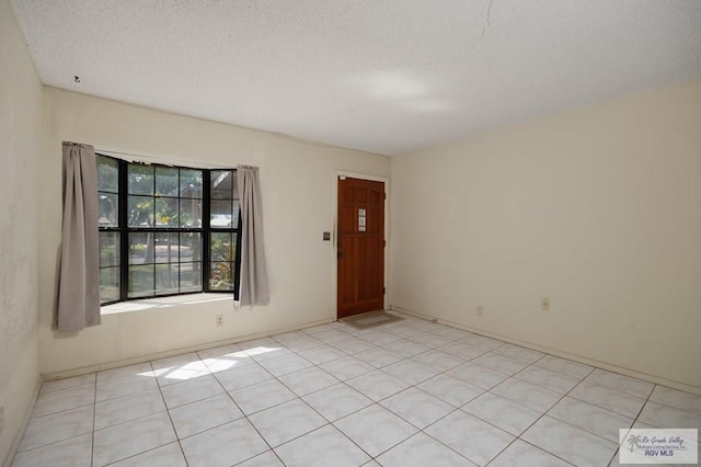 unfurnished room with light tile patterned floors and a textured ceiling