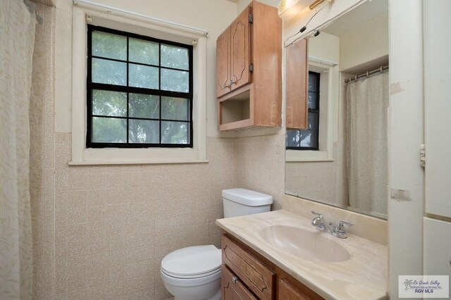 bathroom featuring vanity, toilet, and tile walls