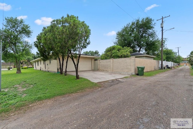 view of property exterior with driveway, a yard, a garage, and fence