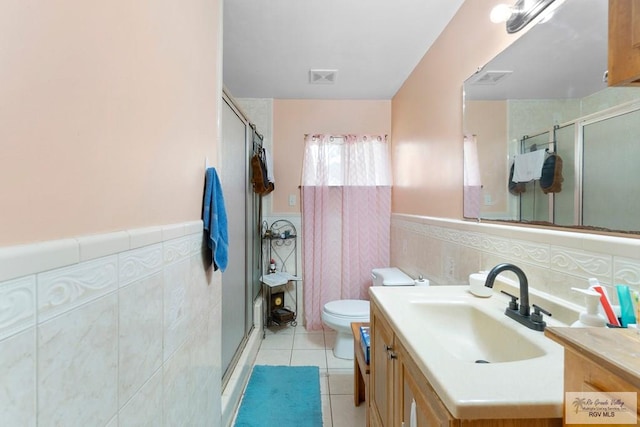 full bathroom with visible vents, a shower stall, a wainscoted wall, and tile walls