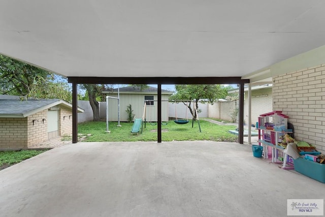 view of patio with an outdoor structure, a shed, a playground, and a fenced backyard