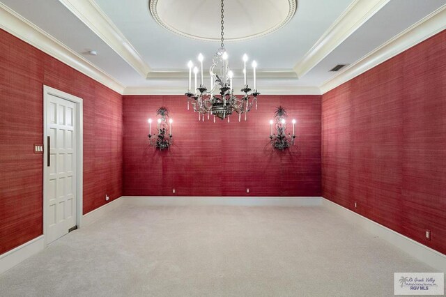 empty room with carpet flooring, a raised ceiling, and an inviting chandelier