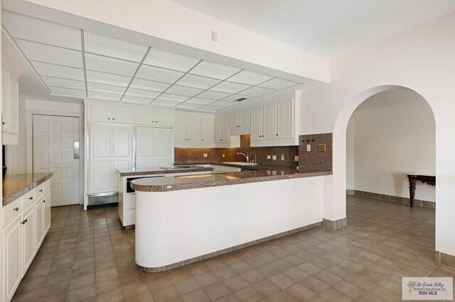 kitchen featuring white cabinets, sink, tasteful backsplash, kitchen peninsula, and stainless steel gas cooktop