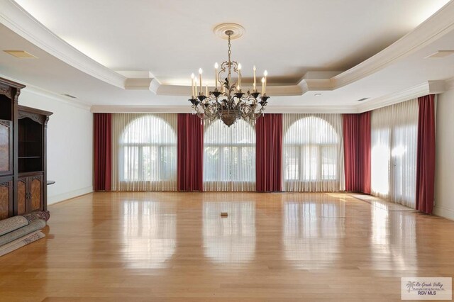 unfurnished dining area featuring a tray ceiling, an inviting chandelier, and plenty of natural light