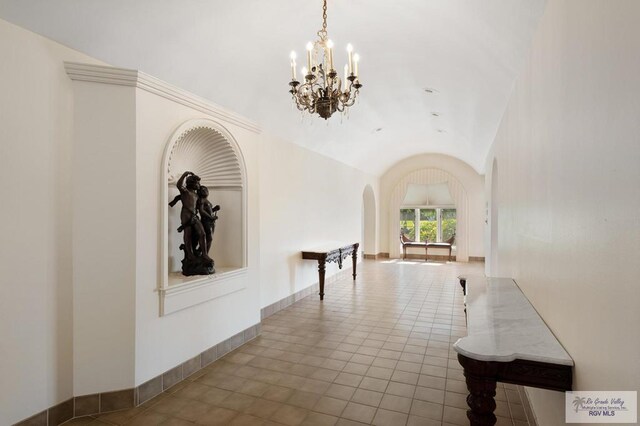 hallway featuring light tile patterned floors, vaulted ceiling, and an inviting chandelier