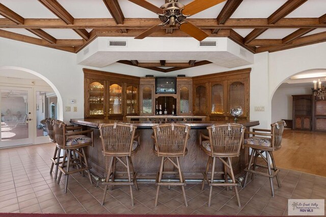 bar with beam ceiling, ceiling fan with notable chandelier, and dark wood-type flooring