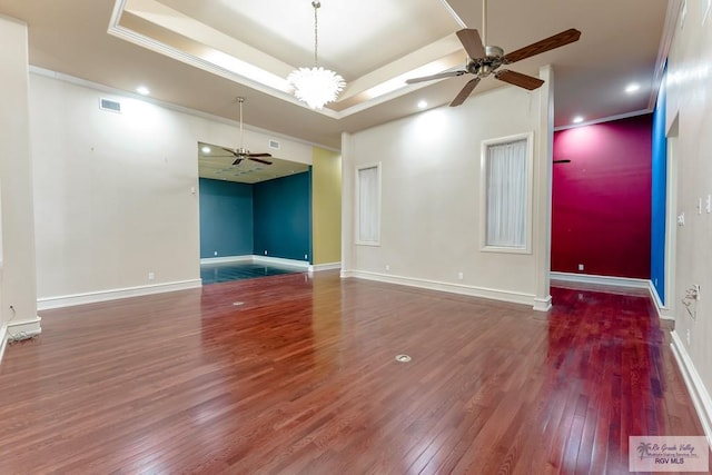 unfurnished room featuring ceiling fan with notable chandelier, dark hardwood / wood-style floors, a raised ceiling, and ornamental molding