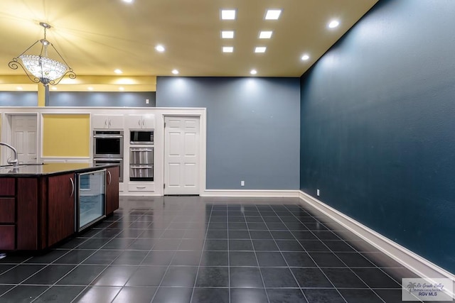 kitchen with stainless steel appliances, dark tile patterned floors, pendant lighting, a notable chandelier, and wine cooler