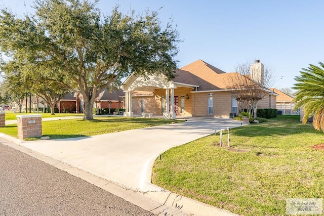 405 E Matz Ave, Harlingen, TX 78550 - view of front facade with concrete driveway, a front lawn, and a chimney