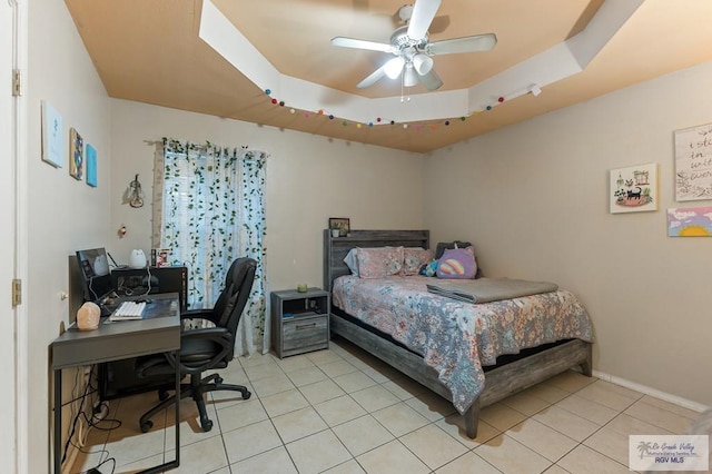 bedroom featuring ceiling fan, light tile patterned floors, and a tray ceiling