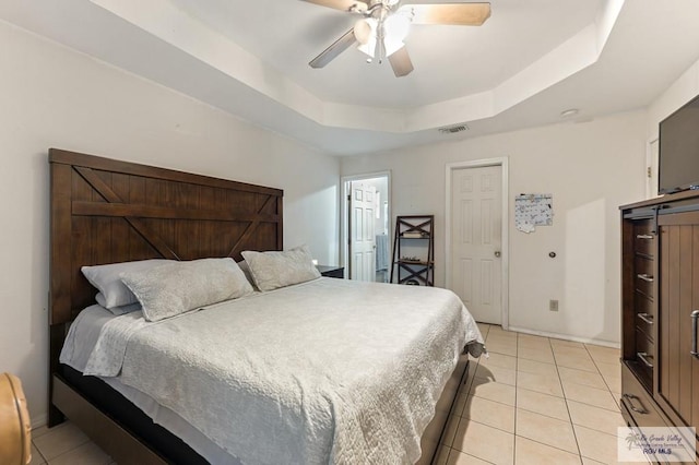 bedroom featuring ceiling fan, a raised ceiling, and light tile patterned floors