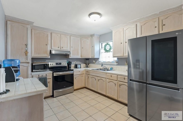 kitchen featuring sink, light brown cabinetry, tile counters, and appliances with stainless steel finishes