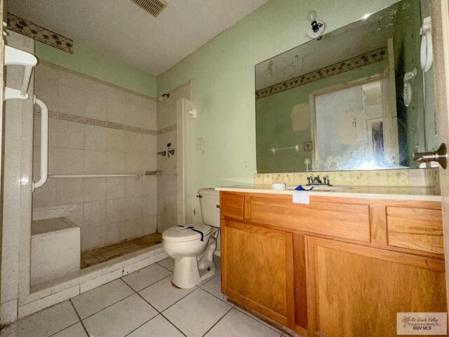 bathroom featuring tile patterned floors, visible vents, toilet, tiled shower, and vanity