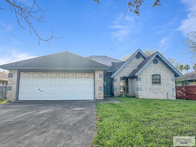 view of front facade with brick siding, a front lawn, fence, a garage, and driveway