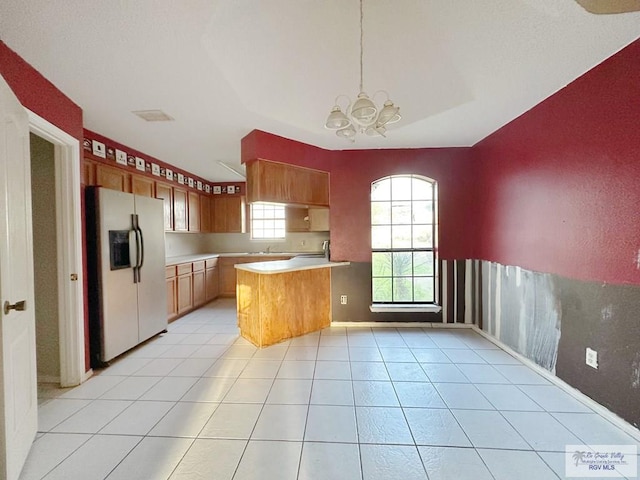 kitchen featuring light tile patterned floors, a peninsula, light countertops, fridge with ice dispenser, and a notable chandelier