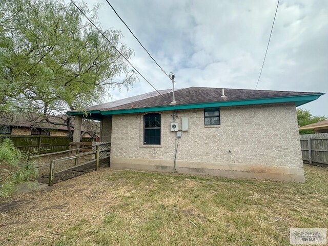 back of property featuring fence and a lawn