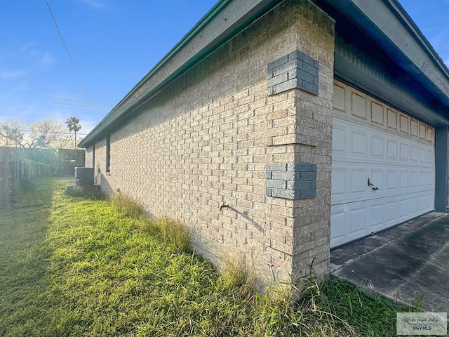 view of home's exterior with brick siding, central AC unit, a garage, and fence