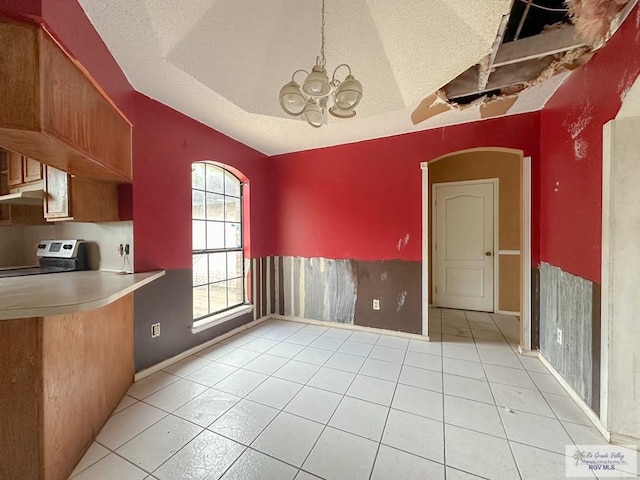 unfurnished dining area featuring light tile patterned floors, a notable chandelier, arched walkways, and a textured ceiling