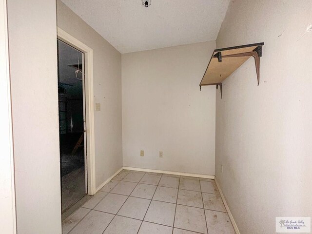 empty room with light tile patterned flooring and baseboards