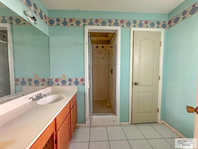 full bath featuring tile patterned floors, a shower stall, a textured ceiling, and vanity