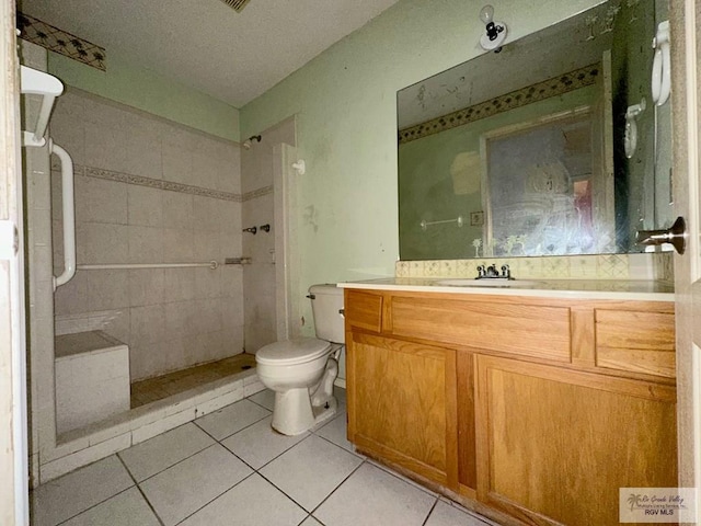 full bath with tiled shower, toilet, vanity, and tile patterned flooring