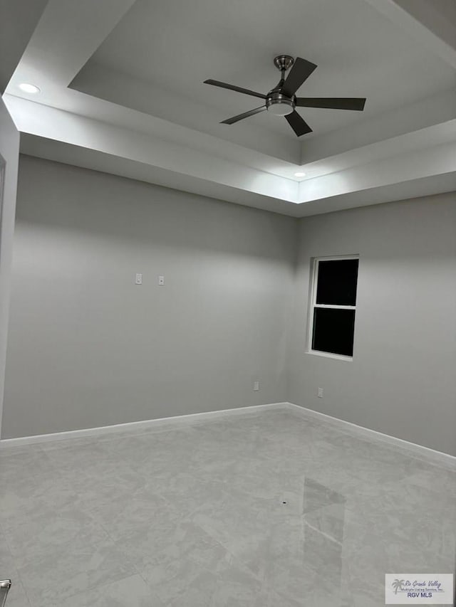 spare room with a ceiling fan, a tray ceiling, recessed lighting, and baseboards