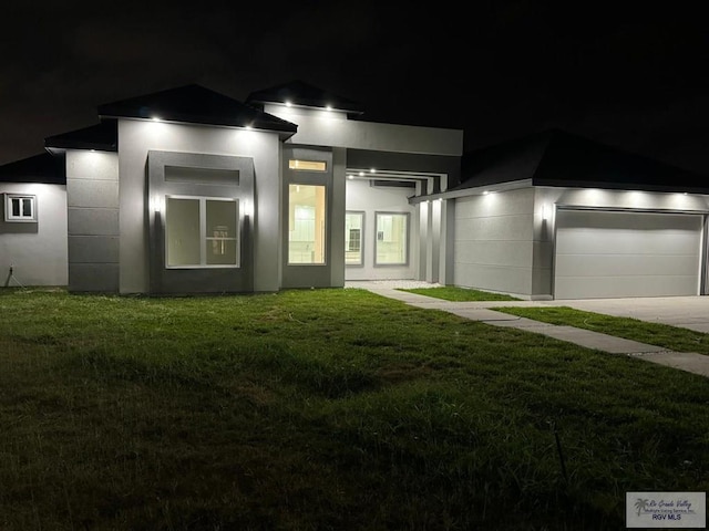 view of front of property featuring a lawn, a garage, stucco siding, and driveway