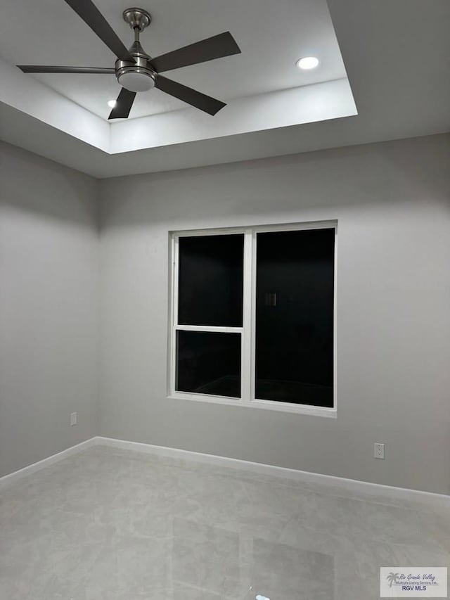 spare room featuring recessed lighting, baseboards, ceiling fan, and a tray ceiling