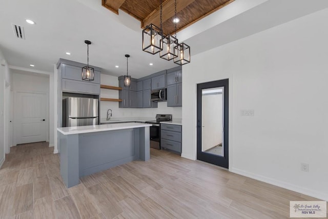 kitchen with gray cabinetry, a center island, hanging light fixtures, and appliances with stainless steel finishes