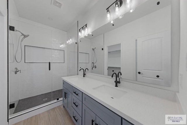 bathroom with hardwood / wood-style flooring, vanity, and an enclosed shower