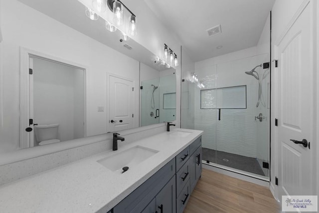 bathroom with vanity, toilet, an enclosed shower, and wood-type flooring